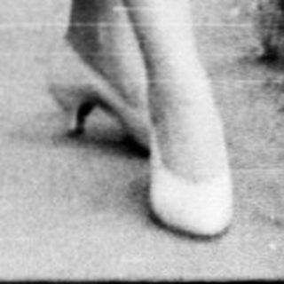 Woman walking alone in park on paved path.