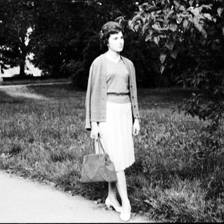 Young woman walking outdoors in vintage dress.
