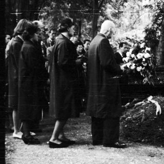 People gathered at a gravesite in a cemetery.