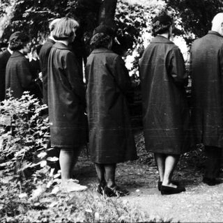 People standing at gravesite in cemetery.