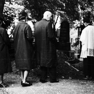 People standing at gravesite in cemetery.