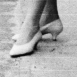 Woman standing under bridge by canal.