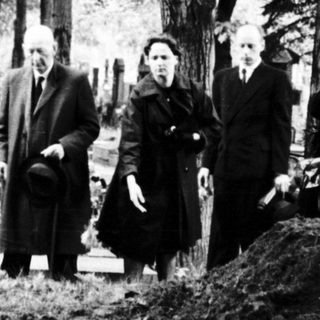 Grave site visit during wartime devastation.