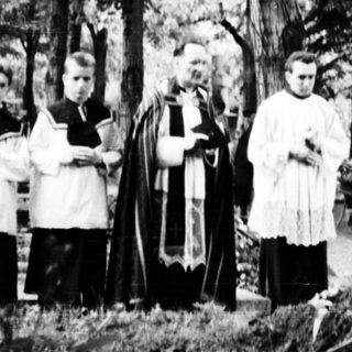 Funeral procession at a gravesite with clergy.