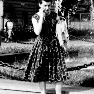 Vintage park scene with woman in 1950s dress near fountain.