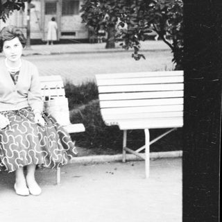 A woman sitting on a bench outdoors.