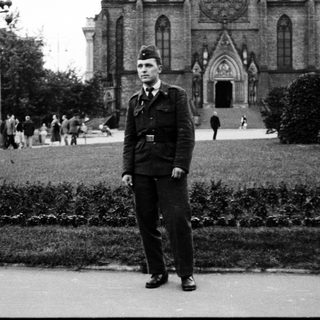 Man in military uniform standing outdoors near cathedral.