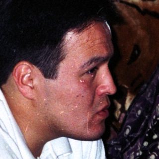 Two people sitting indoors, appearing distressed.