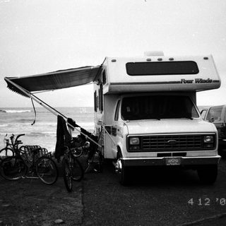 Camper van parked near ocean with bicycles.