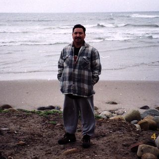 Man standing on beach near ocean with bicycle.