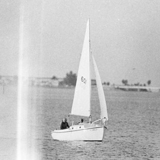 Sailboat cruising on calm water near shore.