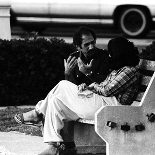 Two men sitting on a bench outdoors.