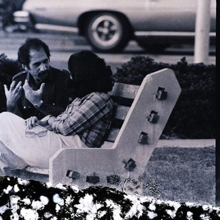 Two people sitting on bench outdoors.