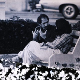 Two people sitting on bench outdoors.