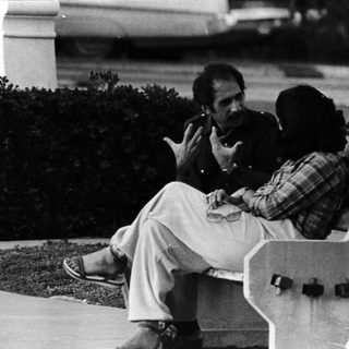 Two men sitting on a bench outdoors.