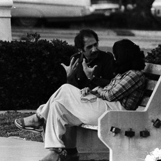 Two men sitting on a bench outdoors.