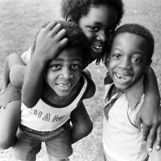 Three joyful children posing happily outdoors.