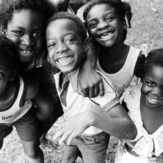 Five joyful children posing happily outdoors.