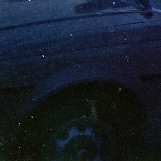 Woman smiling from car roof, suburban driveway.
