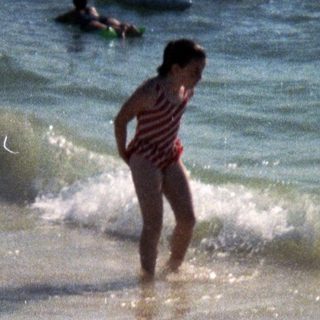 People playing in shallow ocean waves on beach.