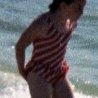 People playing in shallow ocean waves on beach.