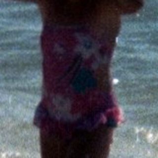 Woman in bikini standing in shallow ocean waves.