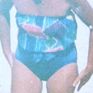 Person in blue swimsuit at beach with cooler.