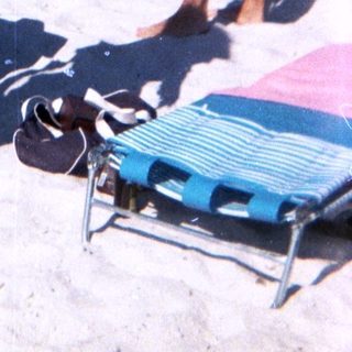 Sunny beach scene with woman in yellow outfit.