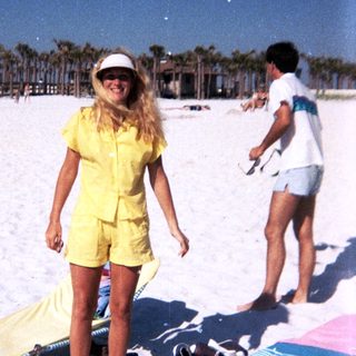 Sunny beach scene with woman in yellow outfit.
