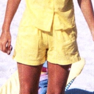 Sunny beach scene with woman in yellow outfit.