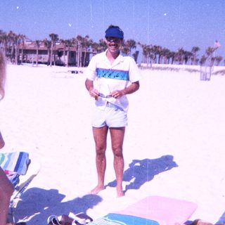 Beach scene with man holding camera, woman standing nearby.