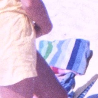 Beach scene with man holding camera, woman standing nearby.
