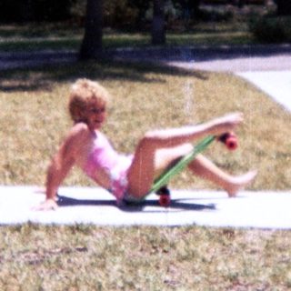 Child sitting on curb in dry grass.