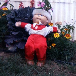 Scarecrow dressed as baby in garden.