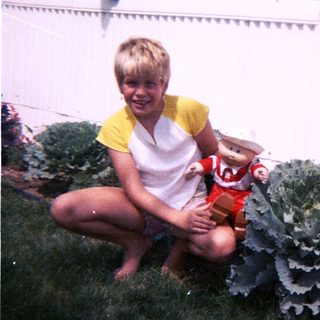 Young boy holding stuffed animal beside large cabbage.