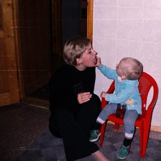 A person feeds a baby sitting on a chair.