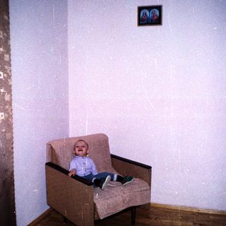 A young child sits in a chair indoors.