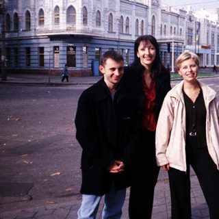 Three people stand in front of a large building.