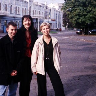 Three people stand in front of a large building.