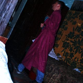 Man in a robe stands in a dimly lit room.