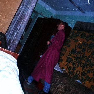 Man in a robe stands in a dimly lit room.