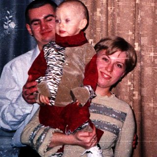 A couple holds a baby in their living room.