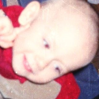 Baby playfully clinging to a person's legs indoors.