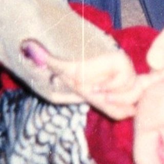 Baby playfully clinging to a person's legs indoors.