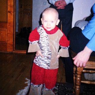 Baby standing, held by an adult, in a home.