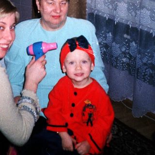 Woman styling hair with a child and another woman present.