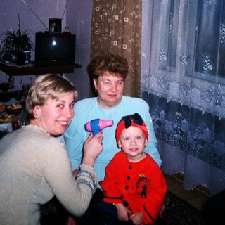 Woman styling hair with a child and another woman present.