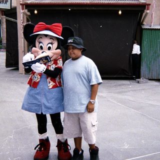 Boy stands with Minnie Mouse at a prop shop.