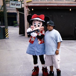 Boy stands with Minnie Mouse at a prop shop.