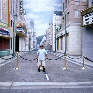 Boy stands on a street resembling Hollywood Boulevard.